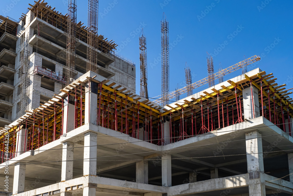 Construction buildings. Unfinished high-rise house. Buildings under construction with temporary supports. Erection of skyscrapers in monolithic way. Buildings under construction under blue sky