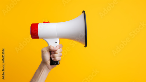 Hand holding a megaphone on a yellow background with copy space