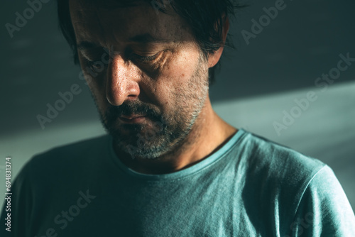 Midlife crisis of middle aged man. Closeup portrait of man in 40s in a depressed state of mind, sad and hopeless. photo