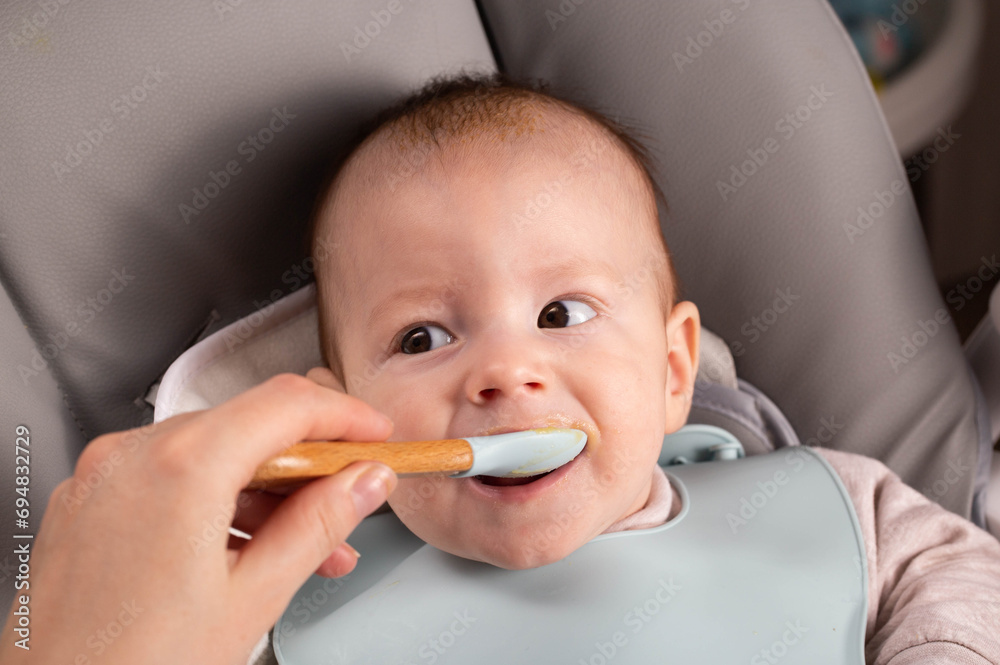 A little boy caucasian has been trying porridge and fruit puree for 6 months. Weight gain in infants, caloric content of food, close-up A little boy caucasian has been trying porridge and fruit puree for 6 months. Weight gain in infants, caloric content of food, close-up