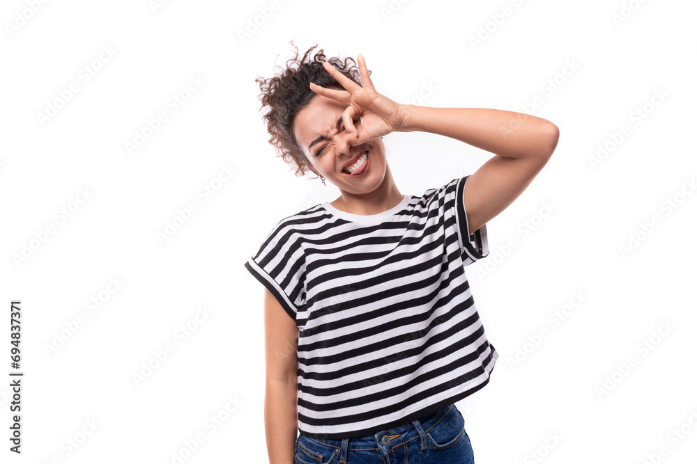 young happy curly brunette lady with black hair dressed in a striped t-shirt rejoices on a white background. people emotions concept young happy curly brunette lady with black hair dressed in a striped t-shirt rejoices on a white background. people emotions concept