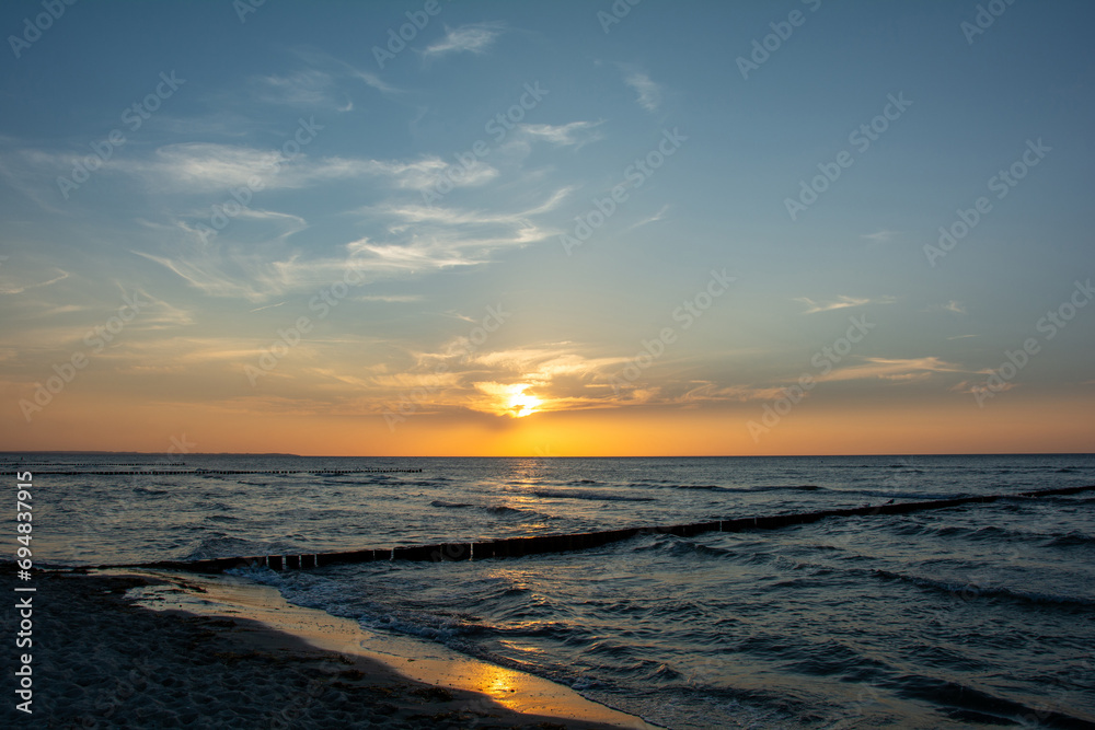 Sunset over the sea with breakwater and beach Sunset over the sea with breakwater and beach