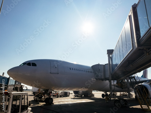 Airplane at airport gate under sunny sky