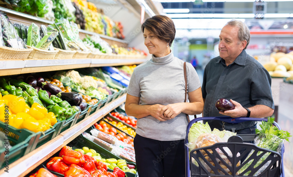 Mature woman and man selecting vegetables in greengrocer