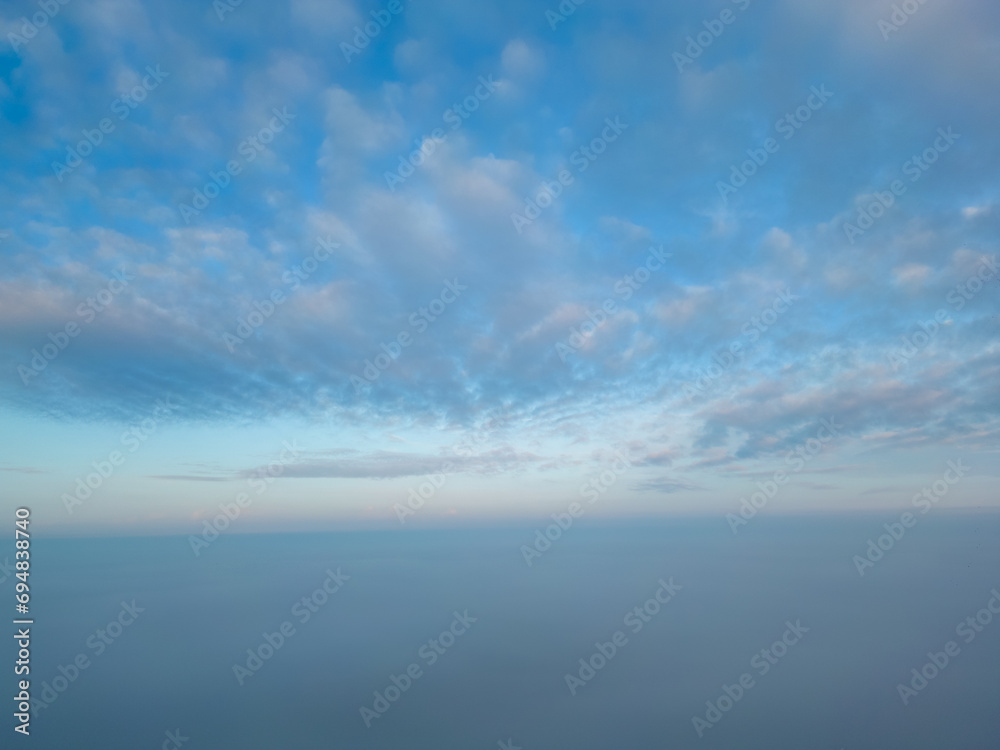 This photograph, taken with a drone above the mist, presents a breathtaking view akin to being above cloud level. The mist blankets the landscape, creating a seamless horizon where sky merges with the
