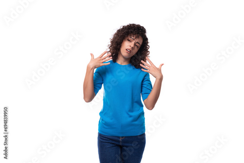 a young woman with a curly hairstyle above her shoulders in blue comfortable clothes feels confident