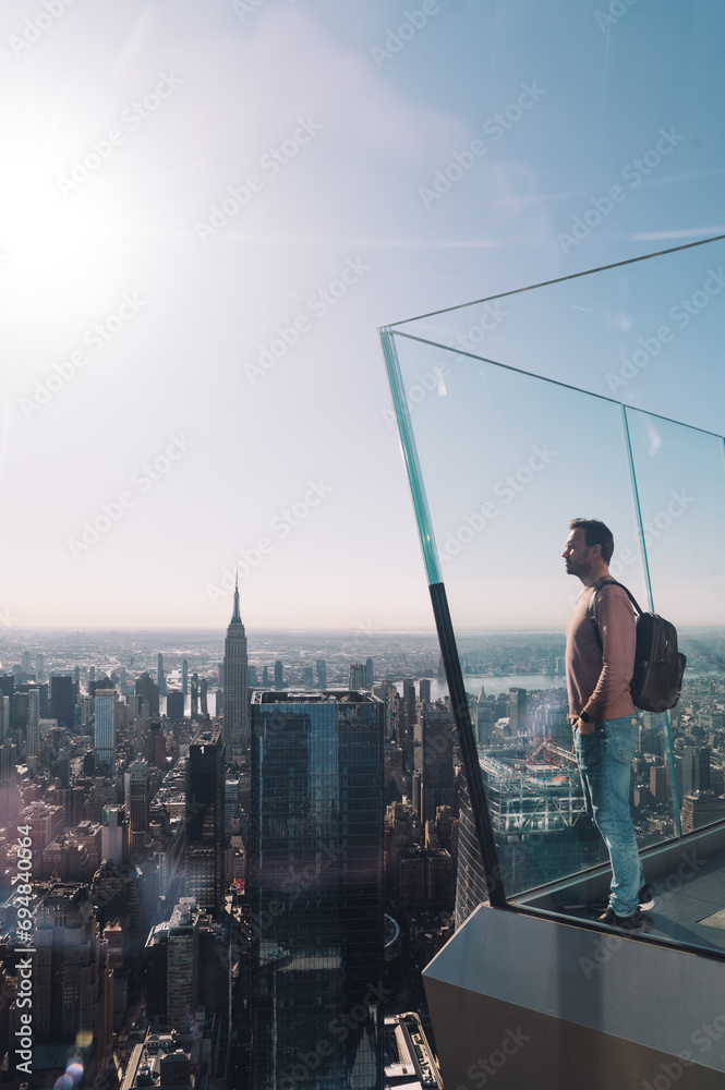 Man gazing at Manhattan's vast skyline from a high-rise Man gazing at Manhattan's vast skyline from a high-rise