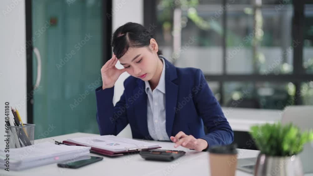 an Asian businesswoman tackles her accounting tasks and projects with a blend of focus and stress, diligently managing her workload on her computer laptop in her office. an Asian businesswoman tackles her accounting tasks and projects with a blend of focus and stress, diligently managing her workload on her computer laptop in her office.