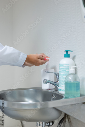 Crop female washing hands with alcohol gel in sink