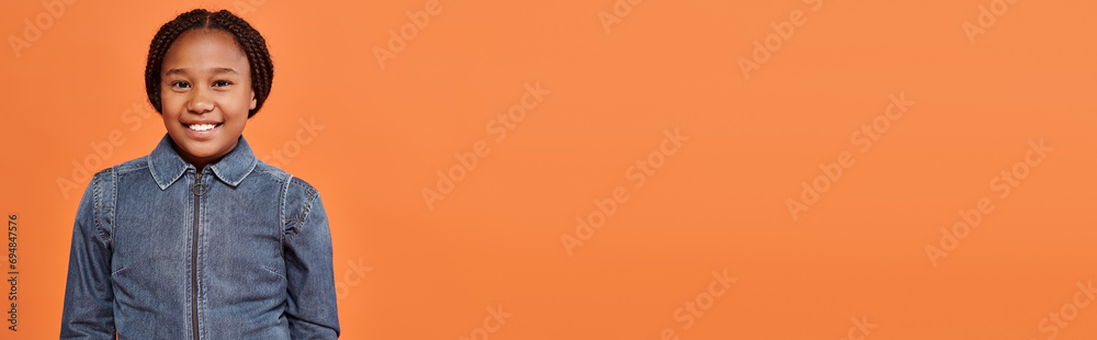portrait of happy african american girl with braids smiling and looking at camera on orange, banner portrait of happy african american girl with braids smiling and looking at camera on orange, banner