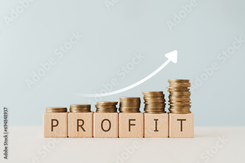 PROFIT text on wooden cube blocks with stack of coin above and increasing graph. For financial investment concept photo