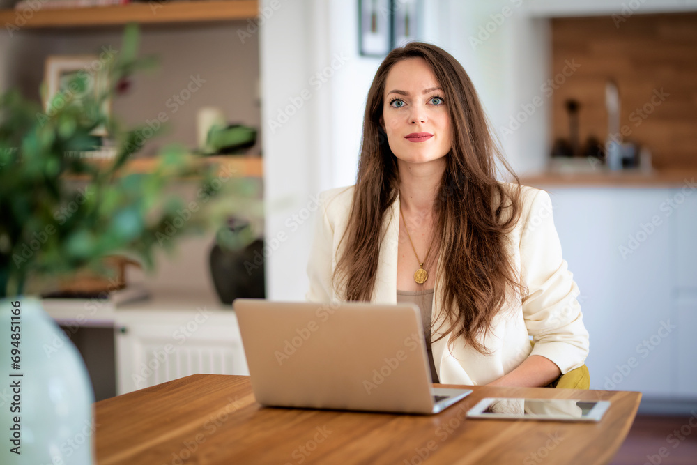 Brunette haired woman sitting at home and using laptop Brunette haired woman sitting at home and using laptop
