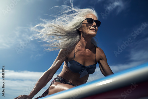 Generative AI image of elegant senior surfer woman enjoying the sun photo