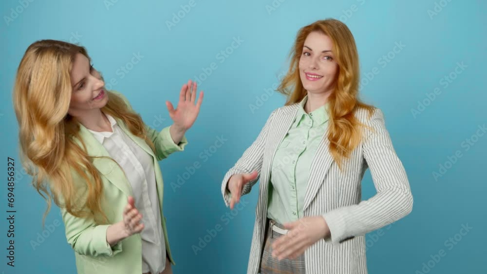 Friends, success and dancing woman celebration winning, excited. Two women sister, businesswoman having fun dance, friendly smiling for goal, discount, sale entertainment, studio on blue, stop motion Friends, success and dancing woman celebration winning, excited. Two women sister, businesswoman having fun dance, friendly smiling for goal, discount, sale entertainment, studio on blue, stop motion