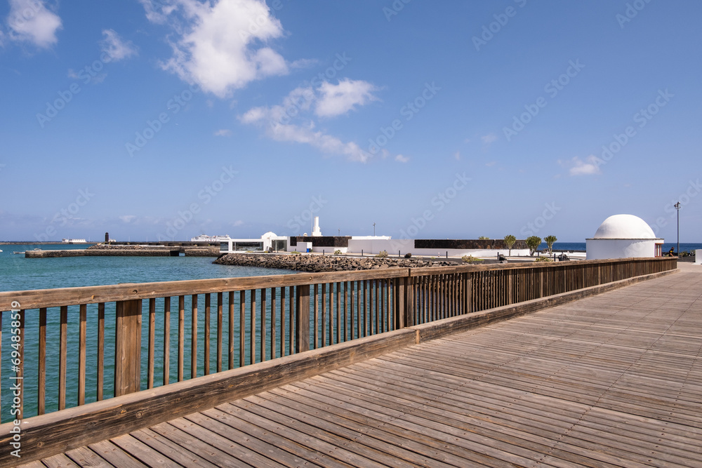 View of the Fermina Islet in Arrecife from a wooden bridge. Turquoise blue water. Sky with big white clouds. Seascape. Lanzarote, Canary Islands, Spain.