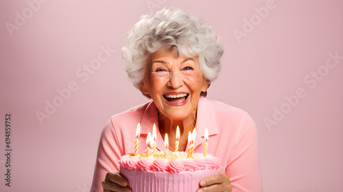 Old woman is blowing out candles on cake