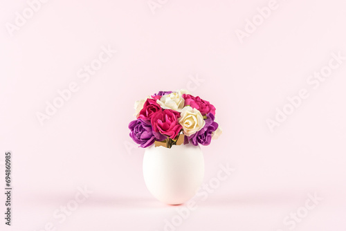 Spring flowers in cracked eggshell against pastel pink background. Easter minimal concept. Creative Happy Easter or spring layout.