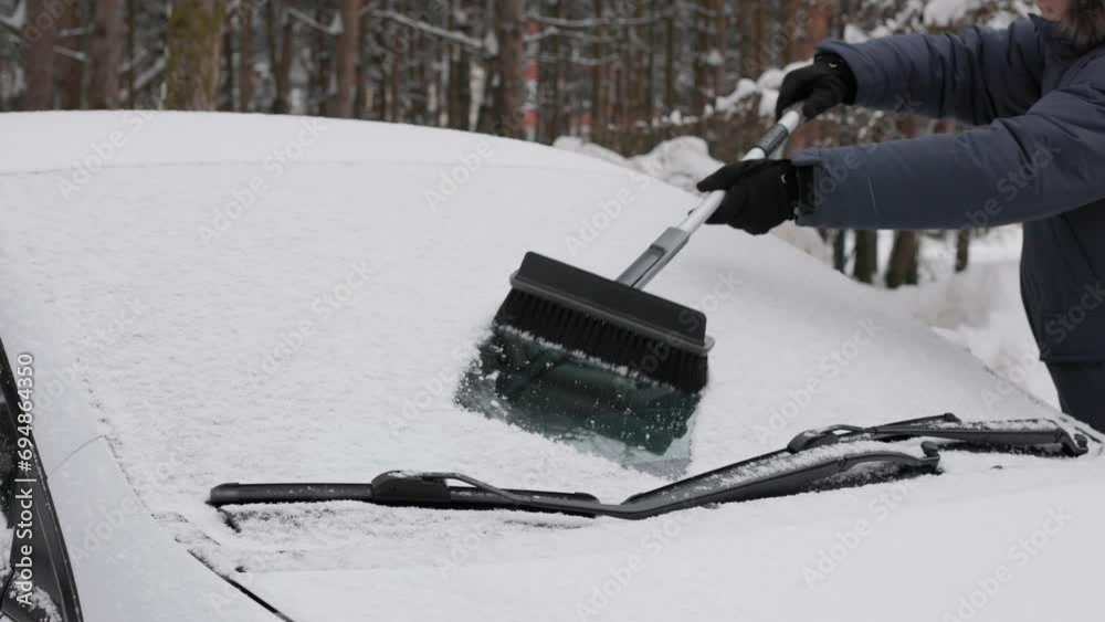 man removing snow from his car’s windshield with big brush man removing snow from his car’s windshield with big brush