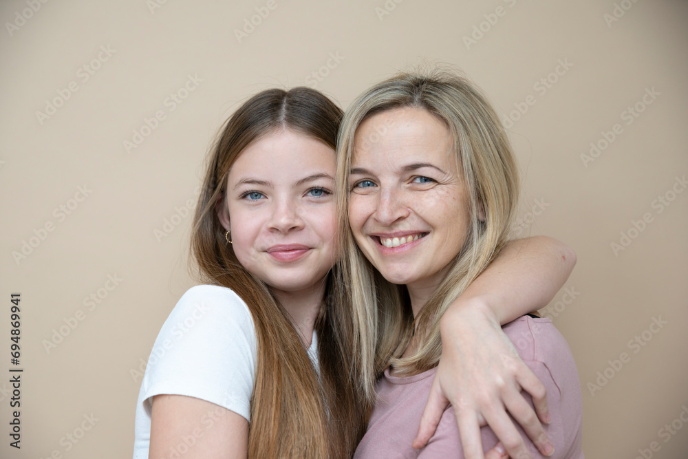beautiful young, teenager girl together with her beautiful mother posing in front of brown background beautiful young, teenager girl together with her beautiful mother posing in front of brown background