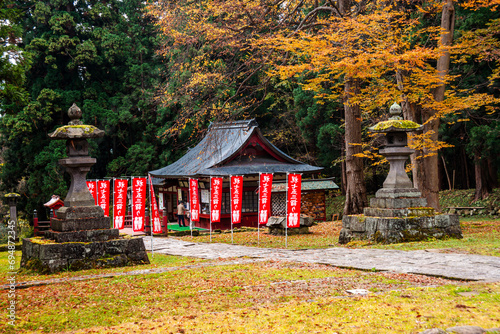 View of a Japanese temple, stone lanterns in an autumnal forest, The Mount Iwaki Shrine, near Hirosaki, North Honshu, Japan photo