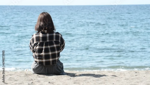 砂浜に座る女性の後ろ姿