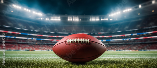 American football ball on the field in the big stadium. Copy free space