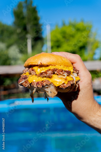 onion smash burger in the hand on a swimmingpool