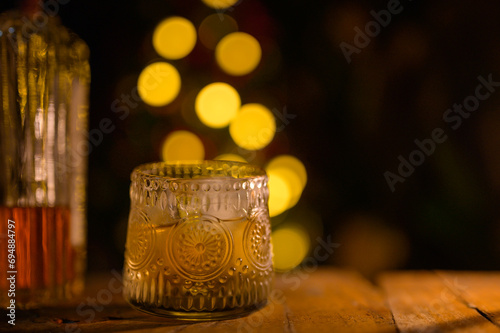 Whiskey glass with ice on a wooden table Beautiful night whiskey with alcohol copy concept on colorful bokeh night background