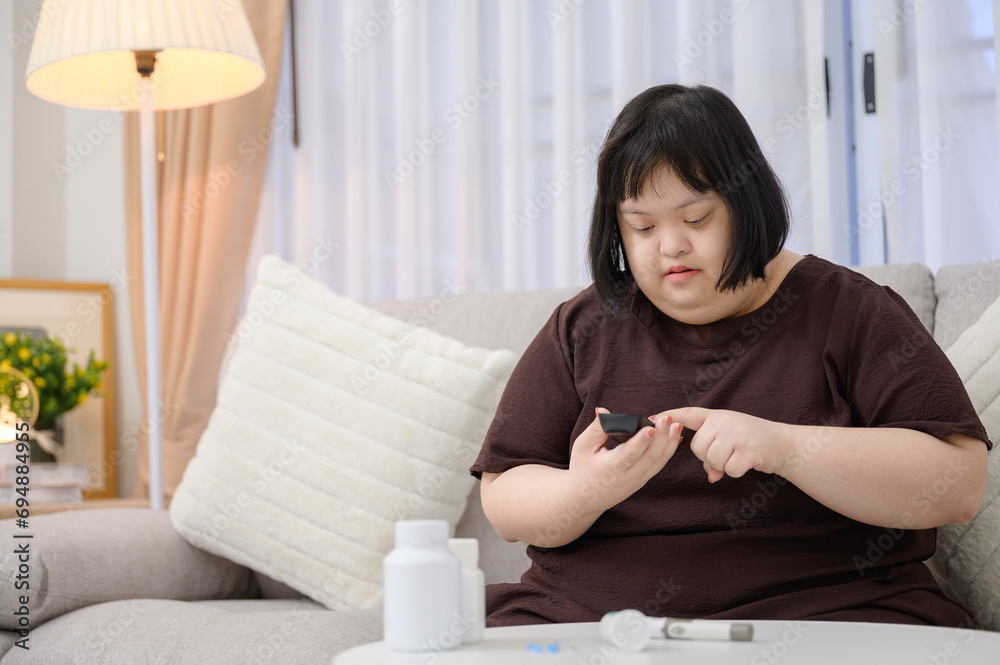 Asian fat woman who Down syndrome A diabetic patient is having blood drawn on his finger to check his diabetes with a blood sugar level meter at home