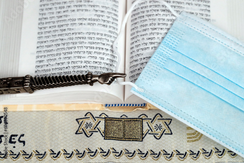 A silver Yad Jewish ritual pointer on a Torah and surgical mask, France photo
