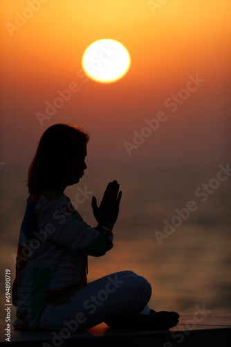 Woman practising yoga pose and meditation at sunset as concept for silence and relaxation, United Arab Emirates photo