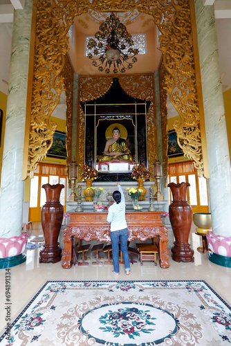 Tinh Xa Ngoc Chau pagoda, Buddhist altar and woman praying to the Buddha, Chau Doc, Vietnam photo