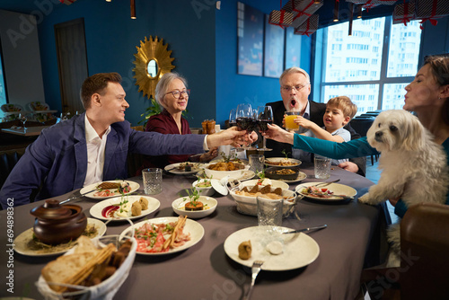 Family holding glasses of wine celebrating winter holiday together in restaurant