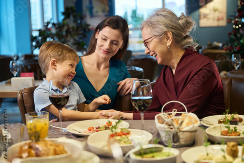 Smiling mature woman enjoying communicating with little boy during Christmas