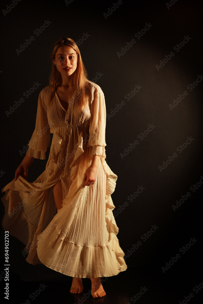 Low key portrait of beautiful standing woman in vintage dress