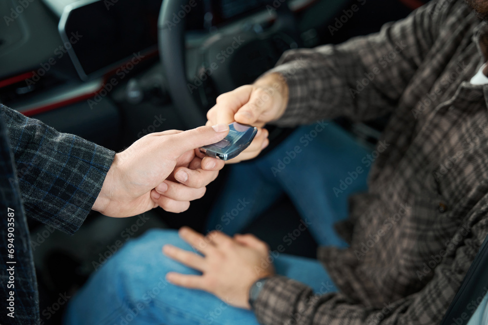 Salesperson working customer at car dealership giving keys to new car owner