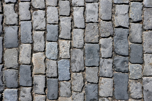 Dark grey cobblestone pavement from old smooth stones as background top view close up photo