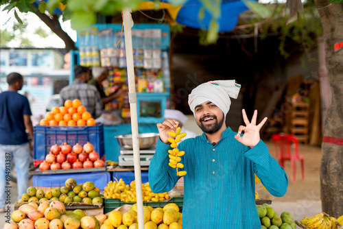Young Indian fruit seller selling or showing his fruit