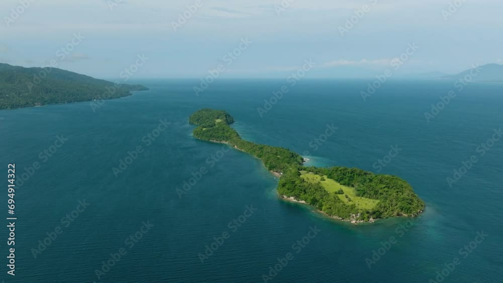 Tropical island with green trees surrounded by blue sea and waves. Blue sky and clouds. Samal Island. Davao, Philippines. Tropical island with green trees surrounded by blue sea and waves. Blue sky and clouds. Samal Island. Davao, Philippines.
