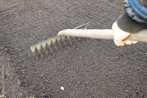 Εκτύπωση καμβά rake - a tool for loosening the soil. Hand holding a rake
