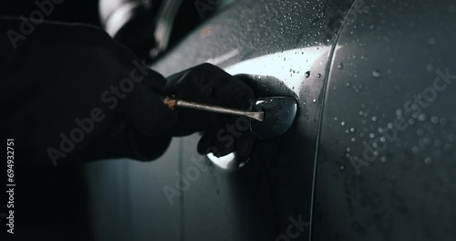 car thief with screwdriver break a door lock and steal a vehicle at night photo