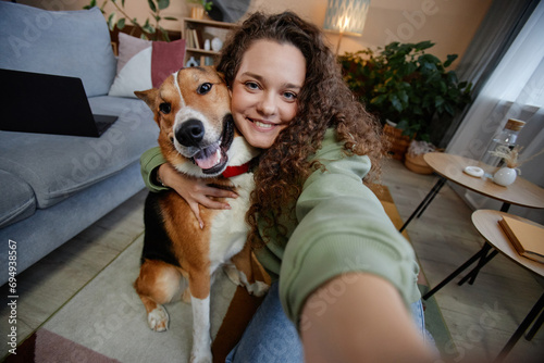Photography POV of young woman taking selfie photo with happy dog at home, copy space
