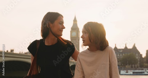 Aesthetic portrait of mother and teenage daughter talking with Big Ben in the background in bright sunlight. photo