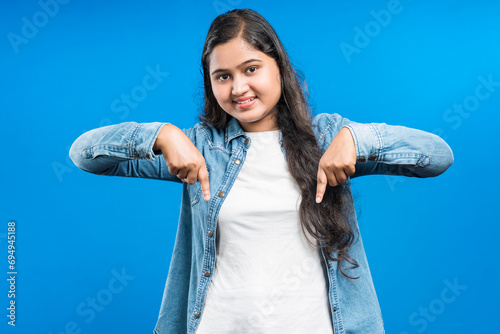 Foto Cheerful Indian female pointing fore fingers downward