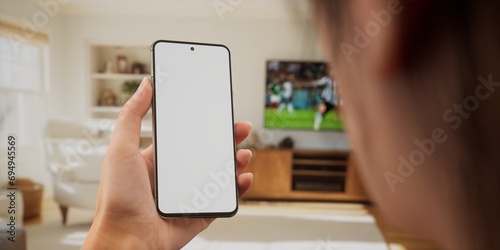 Caucasian female watching football at home, making bets on her phone