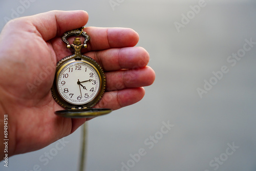 Man's hand holding a pocket watch and blurred background