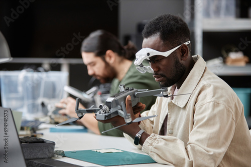 Obraz na plátně Side view portrait of African American man fixing quadcopter drone at workstatio