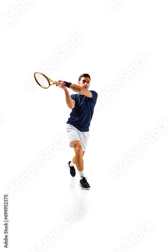 Full-length image of young man, tennis athlete in motion, playing, practicing isolated over white background. Concept of professional sport, competition, game, math, hobby, action