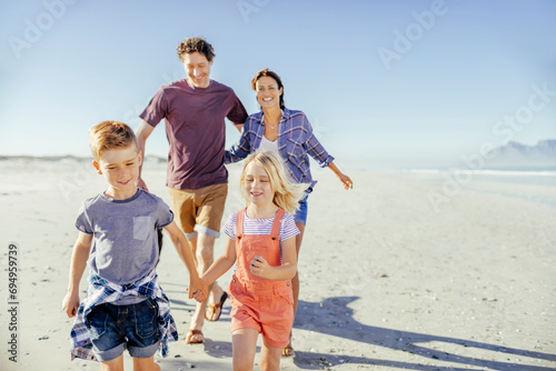 Happy family with small children walking on the beach photo