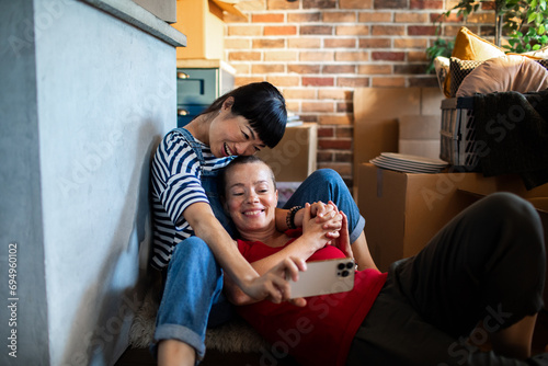 Lesbian couple capturing a selfie amidst moving boxes